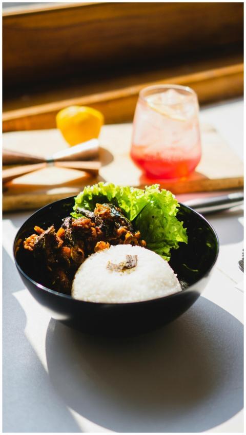 A vibrant bowl of Asian food set beside a refreshi