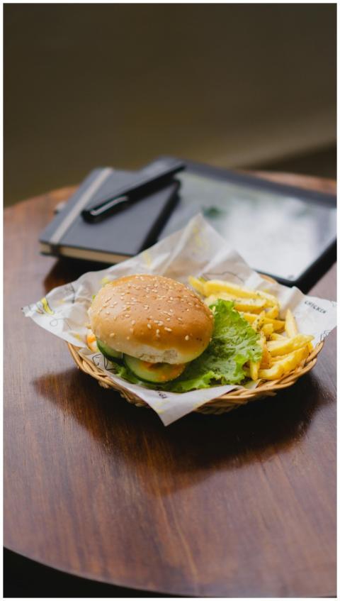 Delicious burger with fries in a basket on a woode