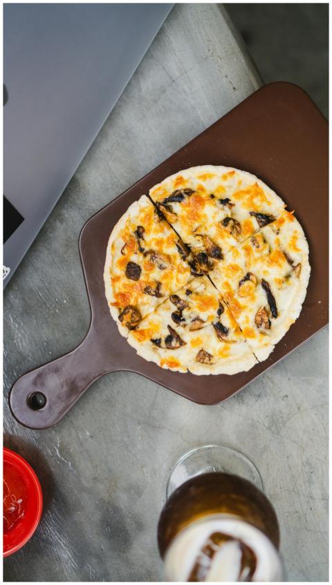 Top view of a sliced mushroom pizza on a wooden bo