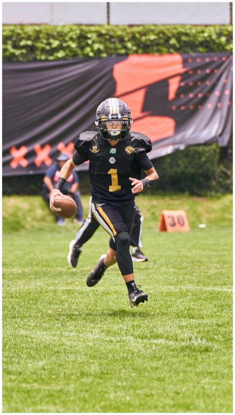 A young athlete in full gear runs with a football