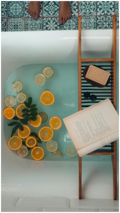 A serene bath setup with citrus fruits, a book, an