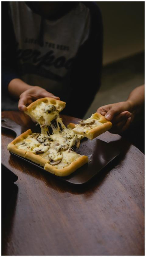 Cheese pizza with mushrooms being enjoyed by two p