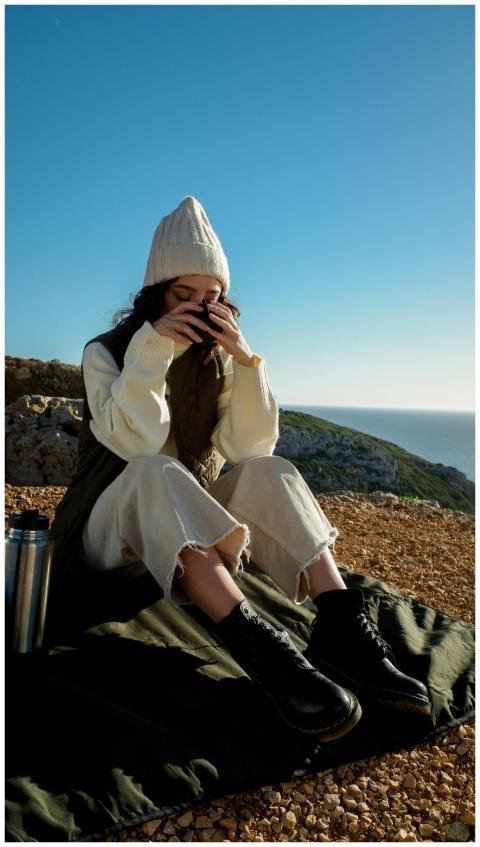 Young woman in a beanie sipping a hot drink outdoo
