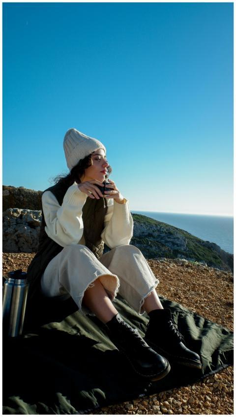 Woman in a beanie and casual attire enjoys a drink