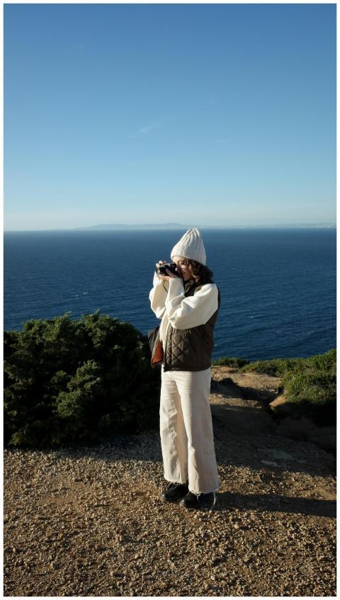 Woman in warm clothing captures stunning ocean vie