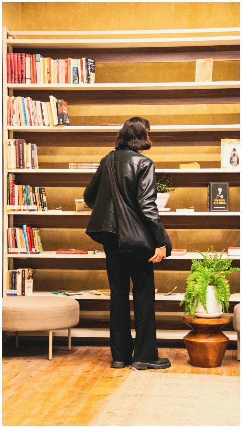 A person in a leather jacket browsing books in a c