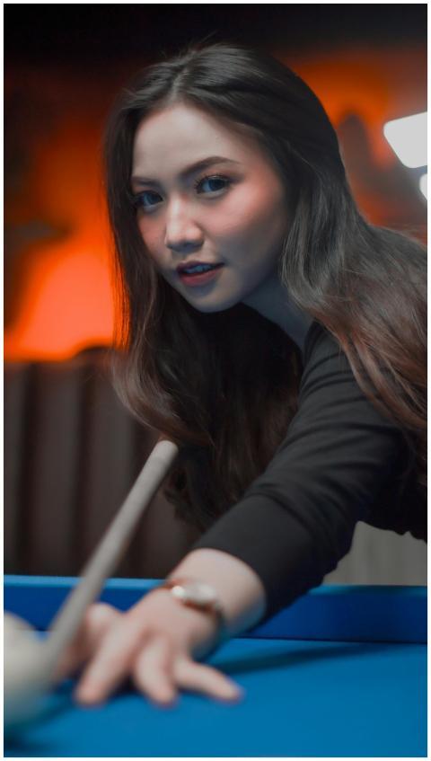A young woman aiming for a shot in a billiards gam
