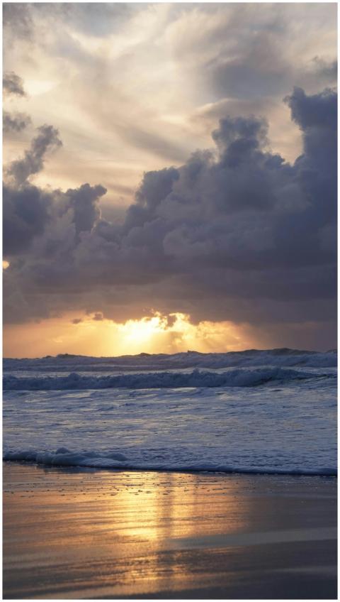 Golden sunset over Lisbon beach with dramatic clou