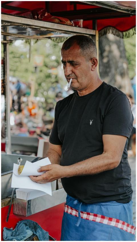 Middle-aged man at street food stall preparing foo