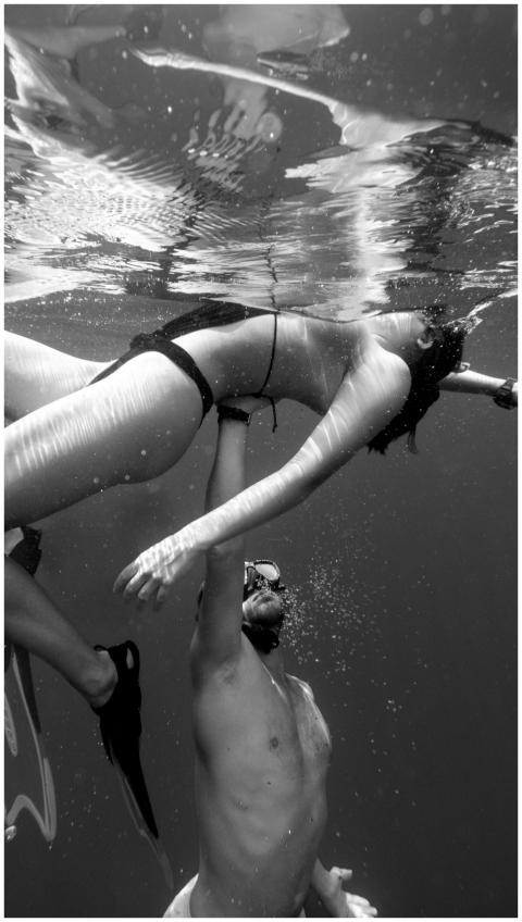 A man and woman snorkeling underwater in a black a