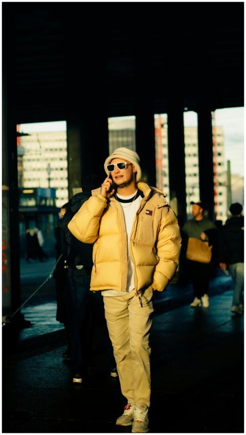 A fashionable man in a yellow jacket walks outdoor