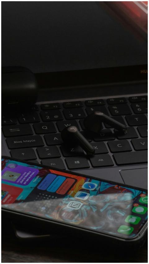 Close-up of a smartphone and wireless earbuds on a