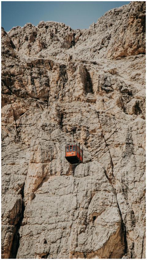 A lone cable car traversing a steep, rugged rock f