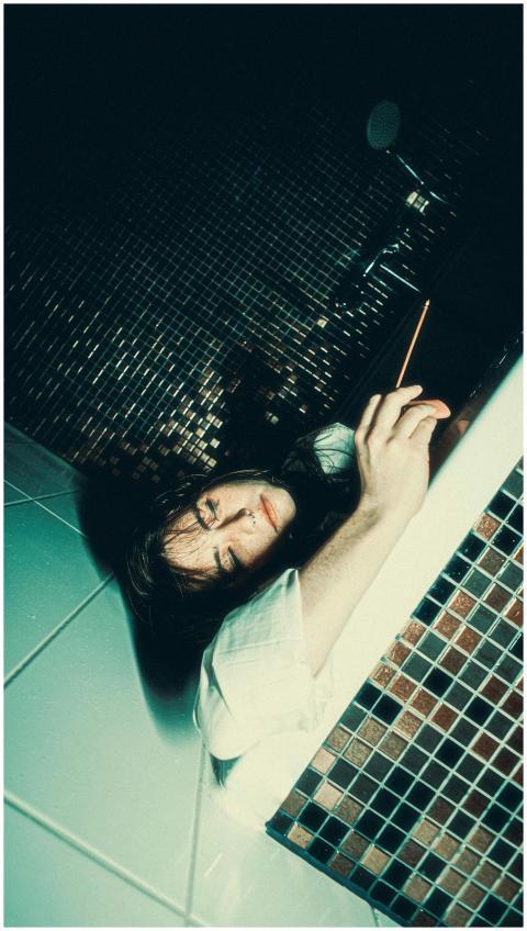 A dramatic portrait of a man lying in a tiled bath