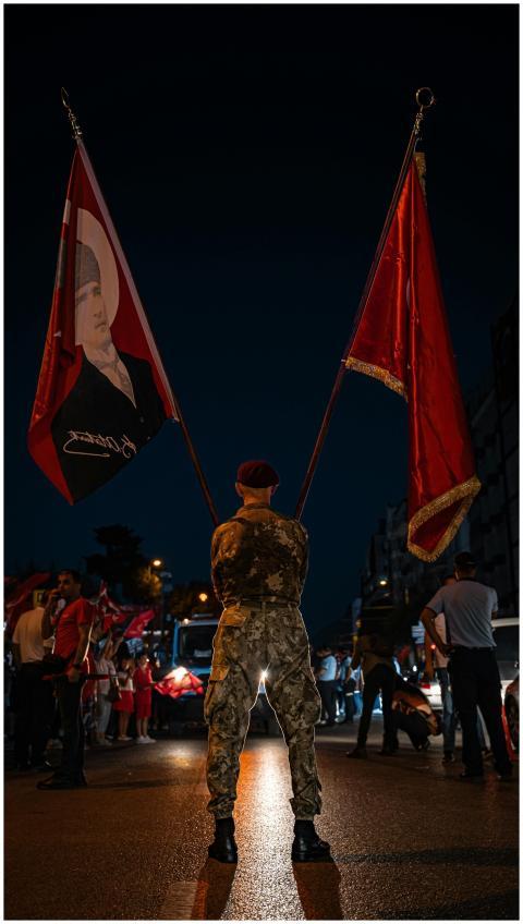 Soldier holding flags during a night event with a