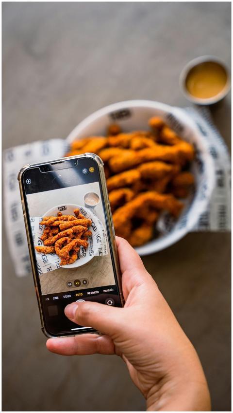 Close-up of hand photographing crispy fried chicke