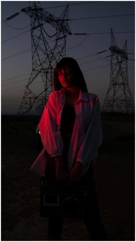 A woman in casual clothing holds a boombox under r