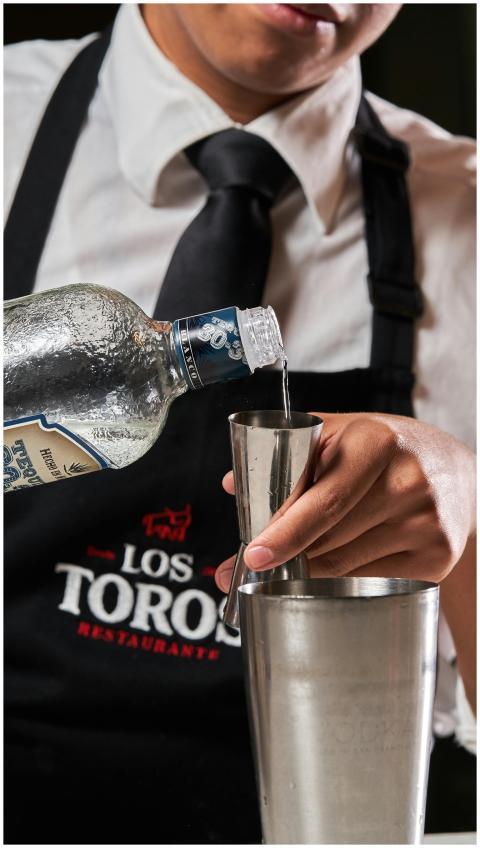Close-up of bartender pouring spirit into jigger a