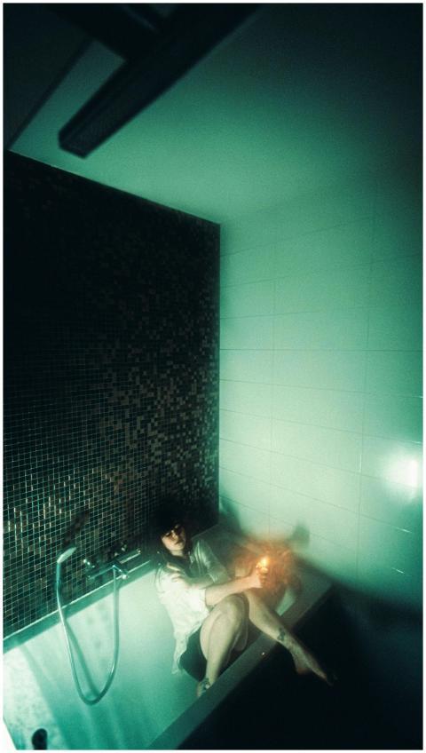 A person relaxing in a bathtub in dim, moody light