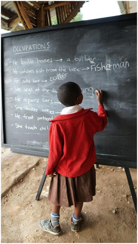 Young student writing on blackboard, practicing oc