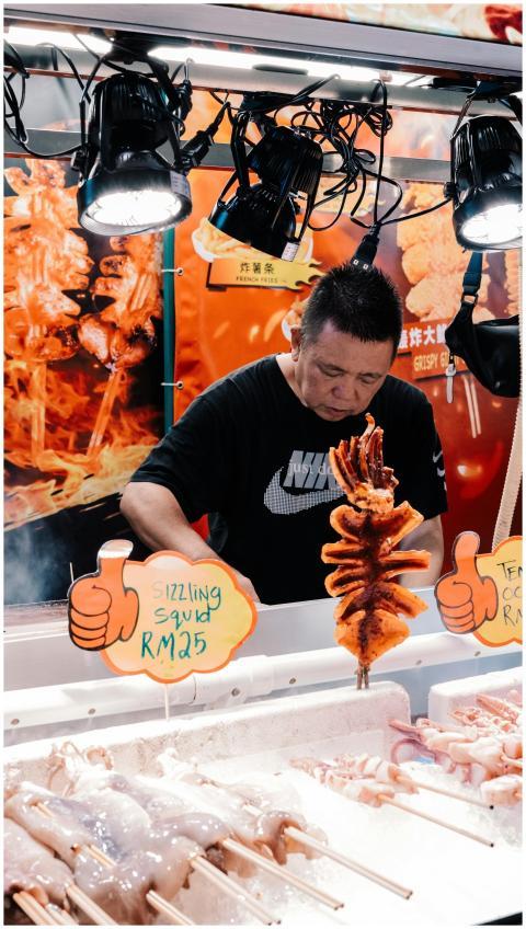 A street vendor cooking sizzling grilled squid at