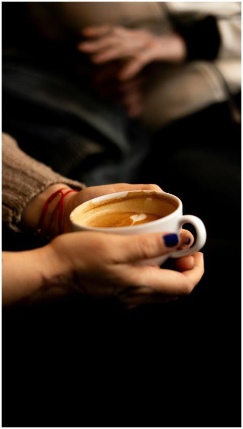 Close-up of hands holding a steaming cup of coffee