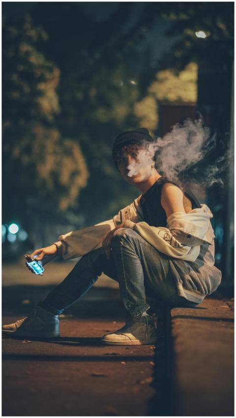 A young man vaping on a street curb in Ho Chi Minh
