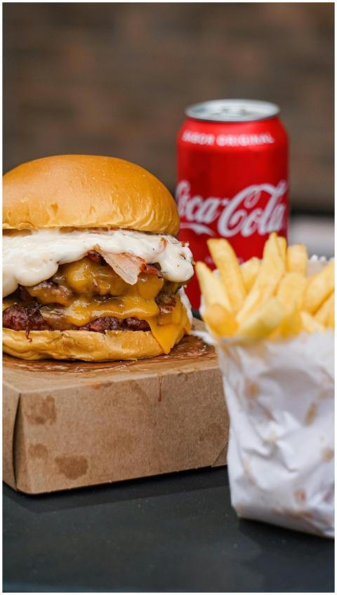 Delicious cheeseburger and fries with a can of Coc