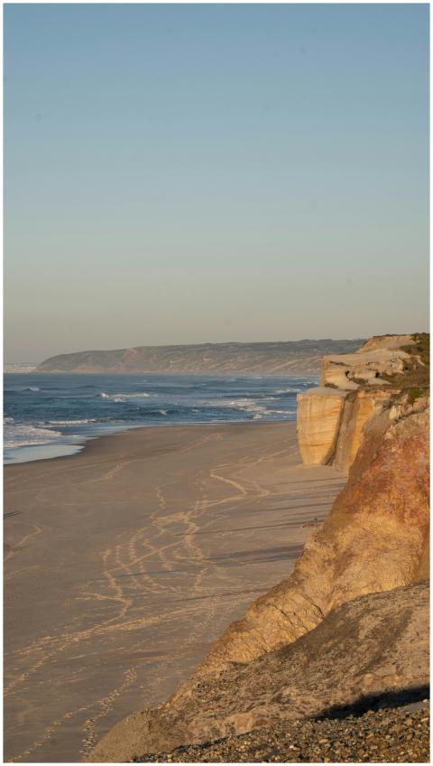 Breathtaking view of sandy beach and cliffs at sun
