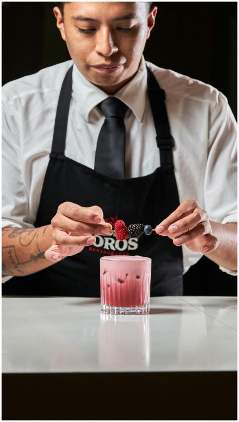 Bartender garnishing a cocktail with fresh berries