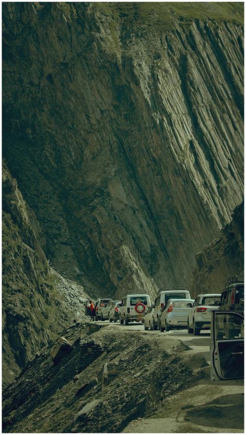 Cars lined up on a mountain road, surrounded by ru