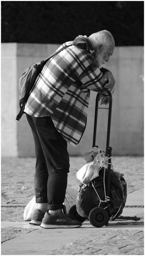 Elderly man in plaid shirt resting on cart in an u
