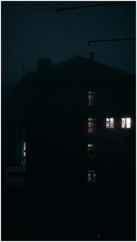 A dark urban building with lit windows, creating a