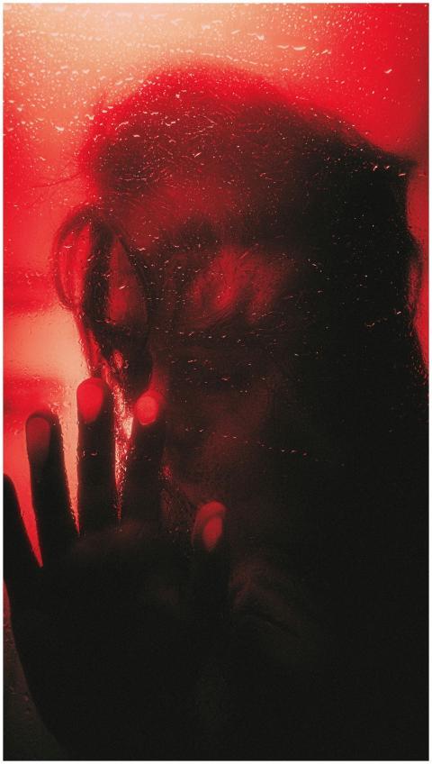 Silhouette of a person behind a foggy glass with r