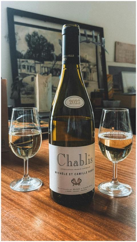 Chablis wine bottle with two glasses on a wooden t