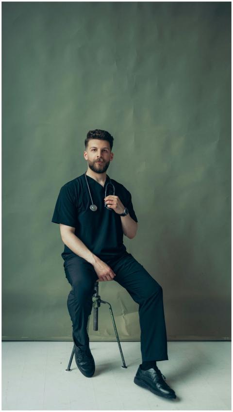 Portrait of a young male doctor sitting indoors wi