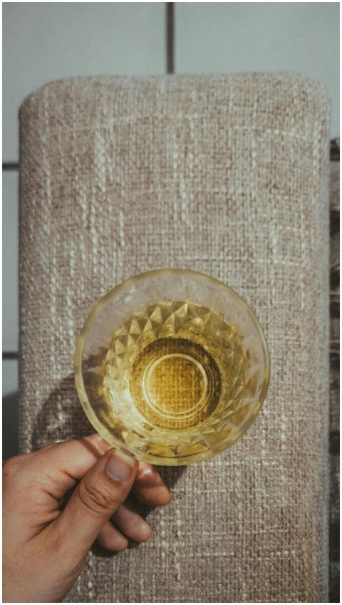 Hand holding a translucent glass with yellow liqui