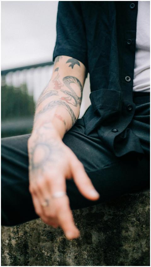 Close-up of tattooed arm of a man sitting outdoors