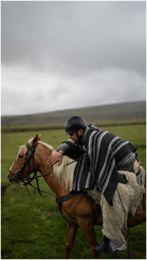 Man wearing a striped poncho riding a horse on a c