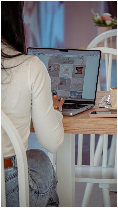 Woman seated at a table, using a laptop indoors wi