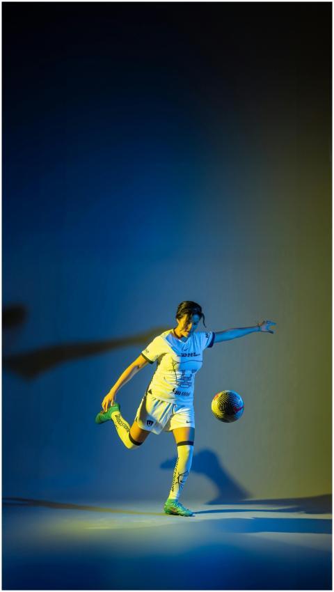 Woman soccer player kicks ball in a vibrant studio
