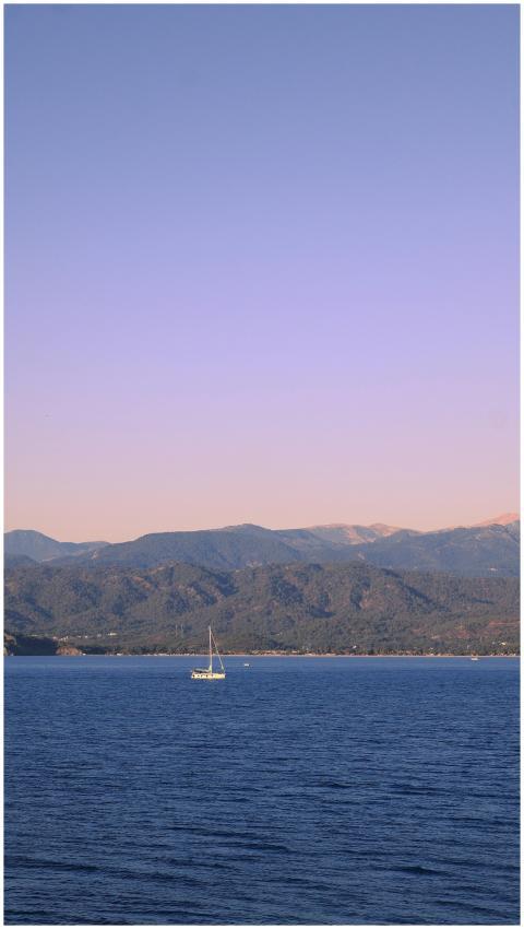 Calm sailboat on a mountain lake at twilight, offe