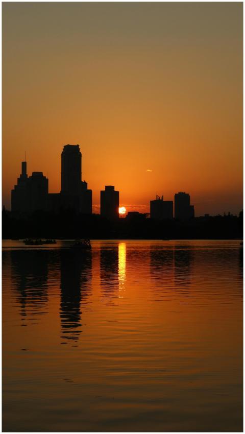 A serene sunset over a city skyline with reflectio