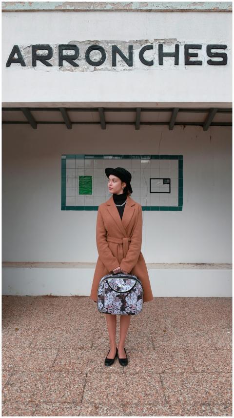 Stylish woman in a coat and beret waiting at Arron