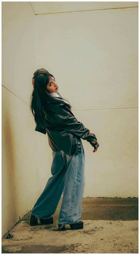 Stylish woman in leather jacket and jeans posing o
