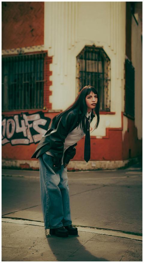 Stylish young woman poses in urban setting with gr