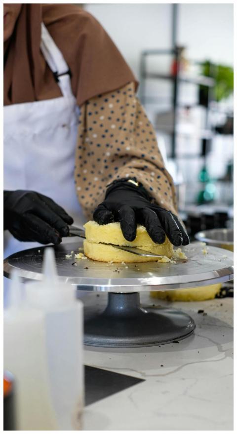 A baker carefully decorates a cake in a modern kit