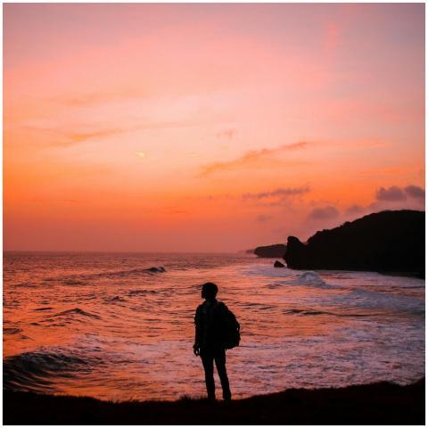 Silhouette of a person with a backpack against a v
