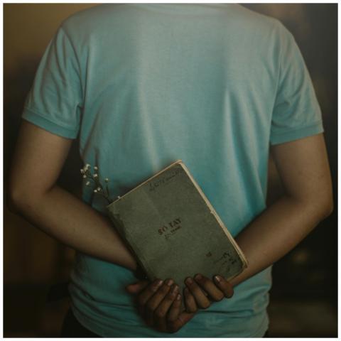 A person in a casual shirt holding a notebook and