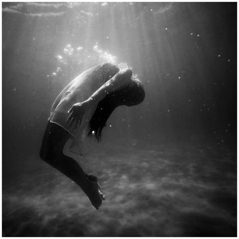 A woman underwater in a dramatic, black and white